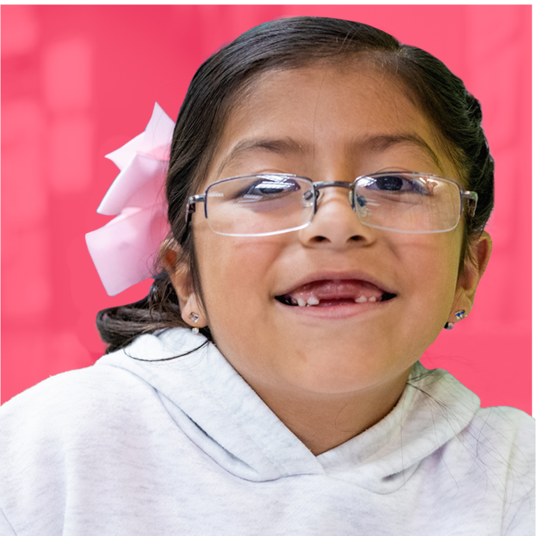 Smiling student wearing glasses and a pink hair bow